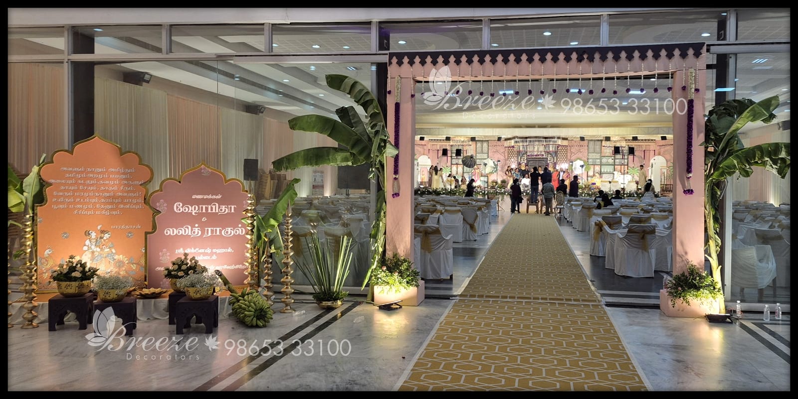 Marriage event management in Coimbatore price list - Traditional wedding hall entrance arch, Tamil welcome signage, banana trees, carpeted walkway, and stage setup by Breeze Decorators